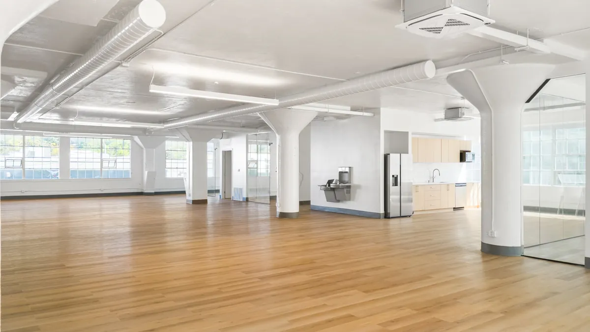 Finished second-floor suite with oak floors, white columns and a glass conference room