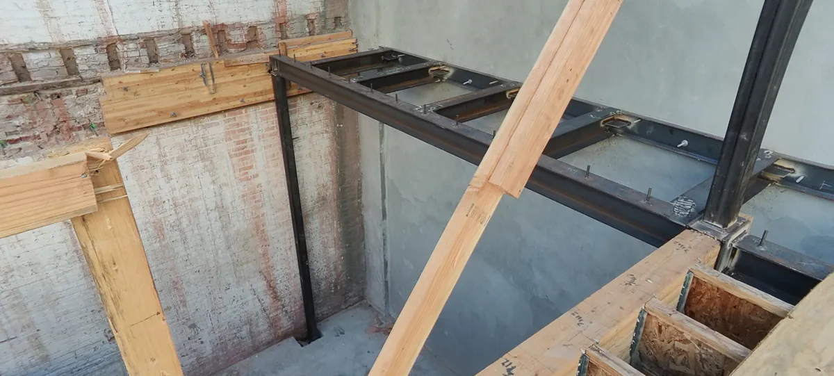 New steel beams and wood floor framing against the original brick wall at 63 Bluxome St